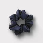 Duo de scrunchies de cetim mate e seda chifon, um liso e um com padrão triangulos, ambos em tons de azul.