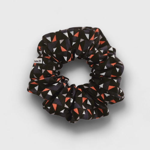 Duo de scrunchies de cetim mate e seda chifon, um liso e um com padrão triangulos, ambos em tons de azul.