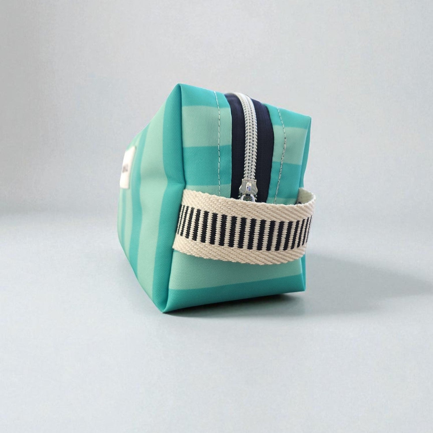 Necessaire impermeável em nylon as riscas e forro de algodão.
